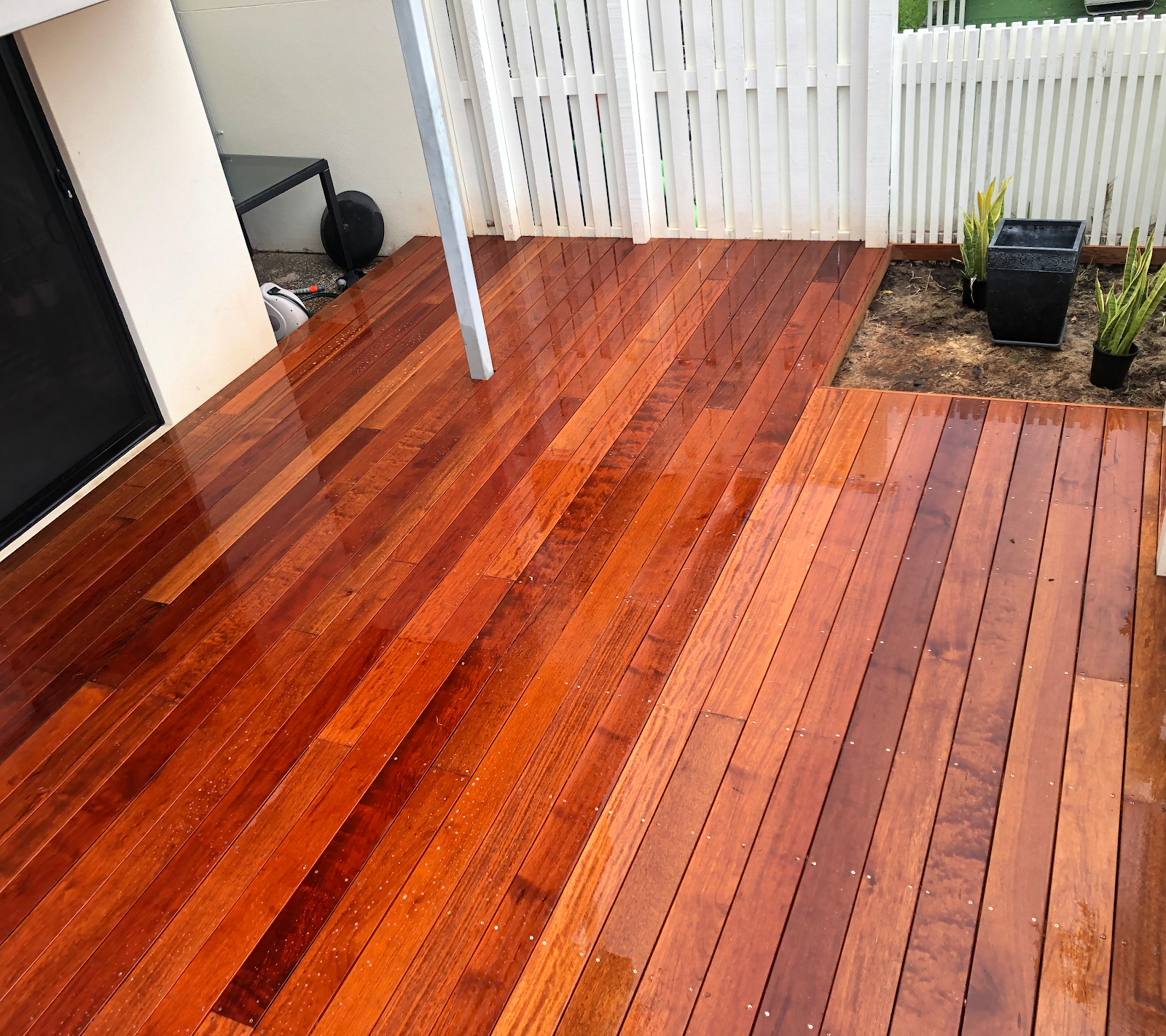 Close up of freshly oiled spotted gum decking beside a white fence