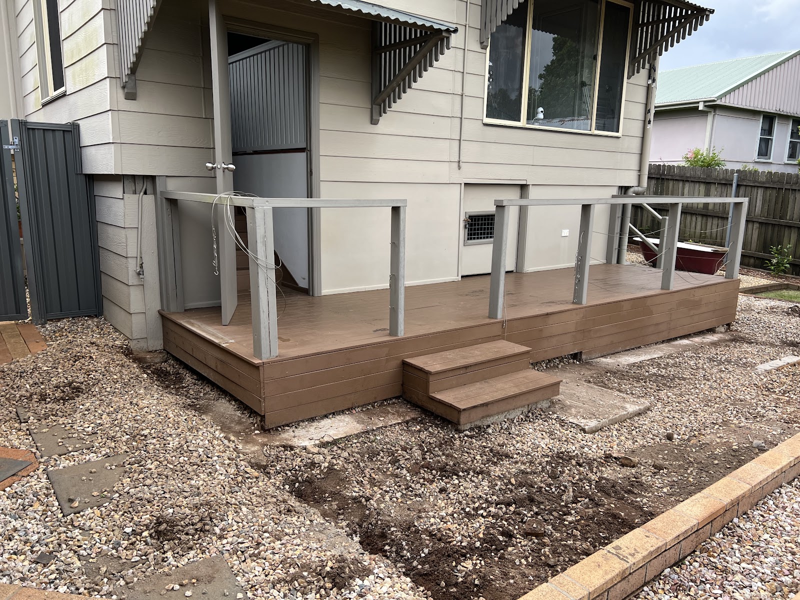 New composite deck and steps under construction behind a raised house