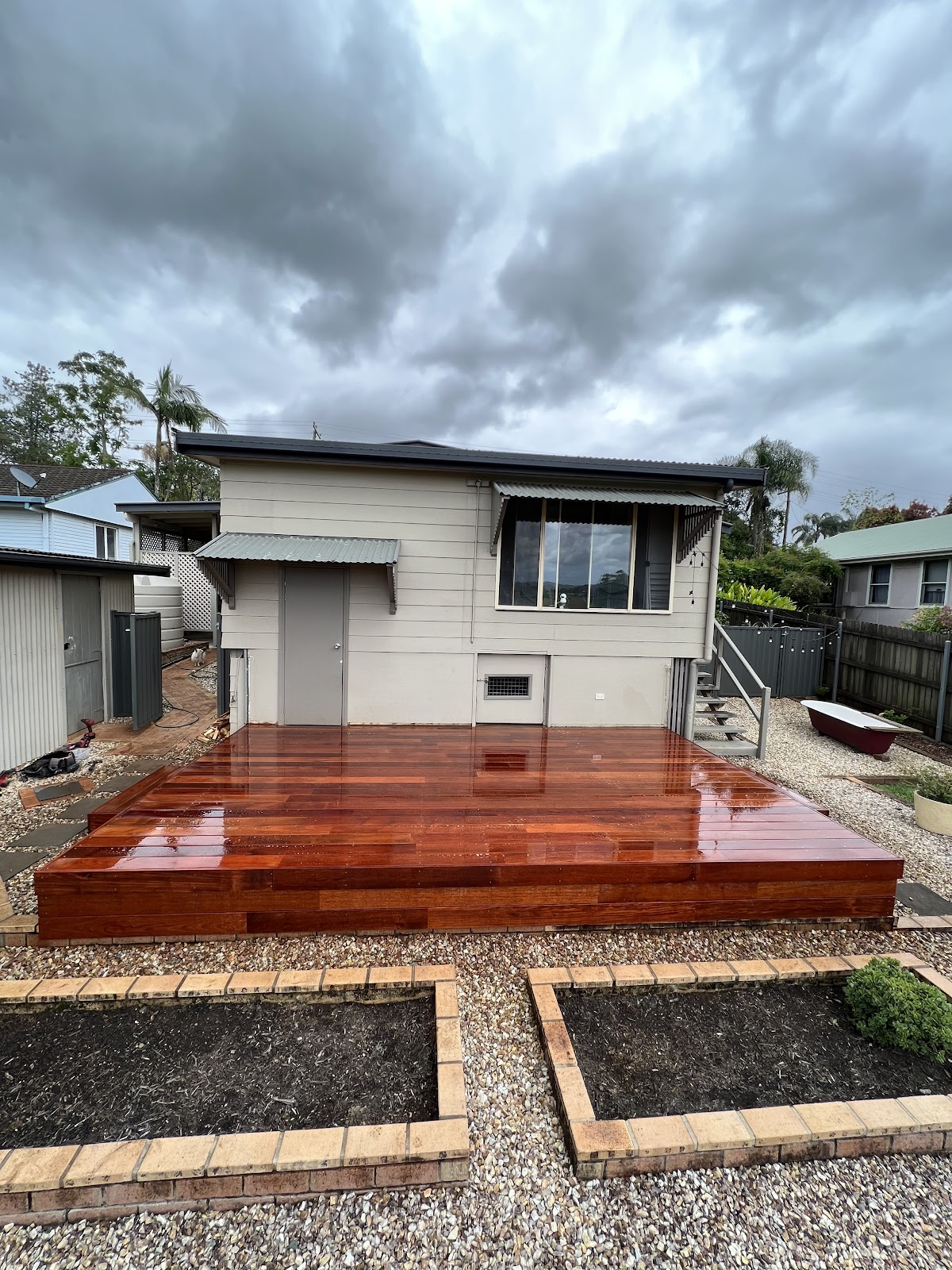 Oiled timber deck across the back of a small weatherboard house