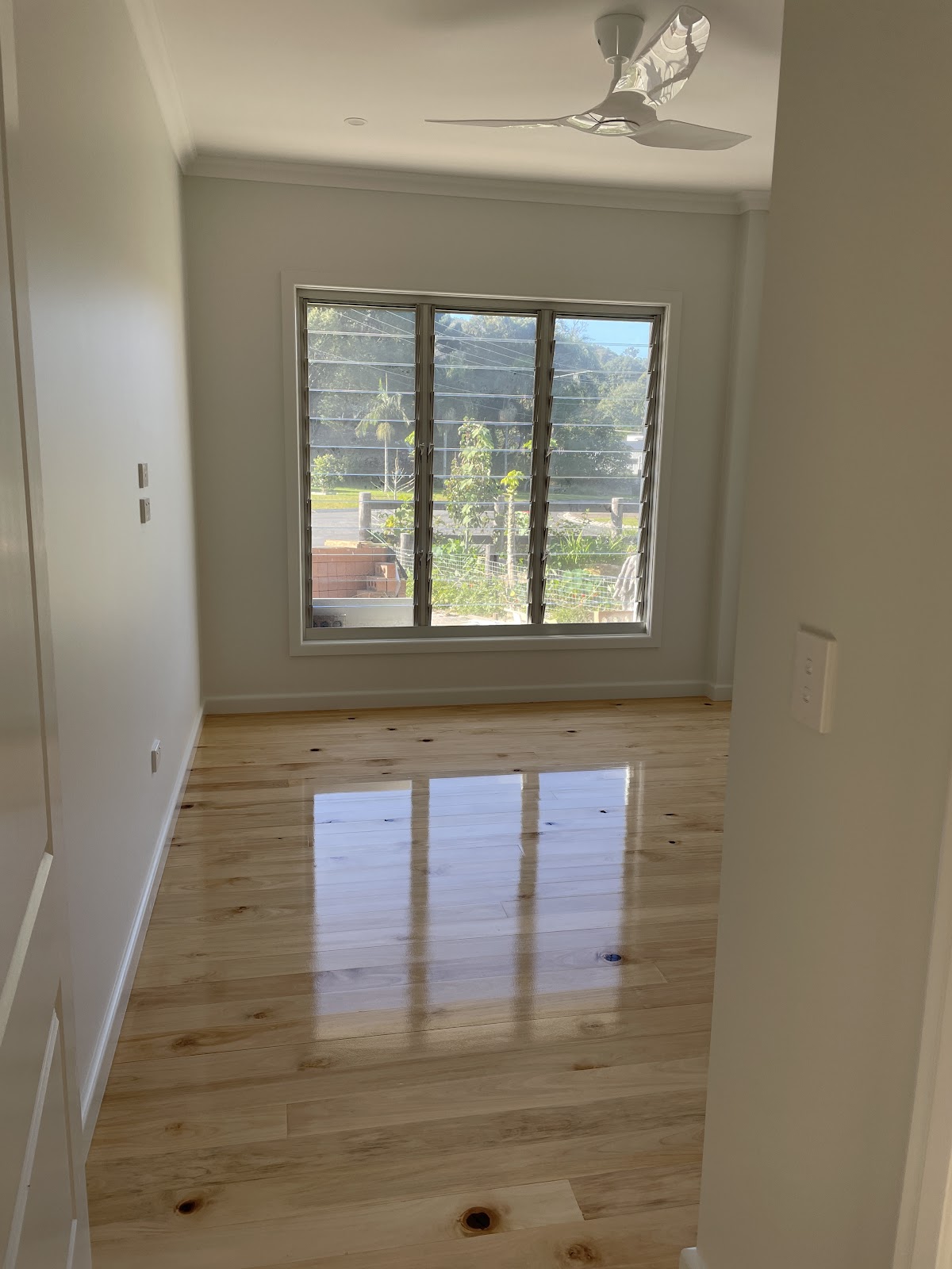 Glossy new timber floor in a renovated room with a louvre window